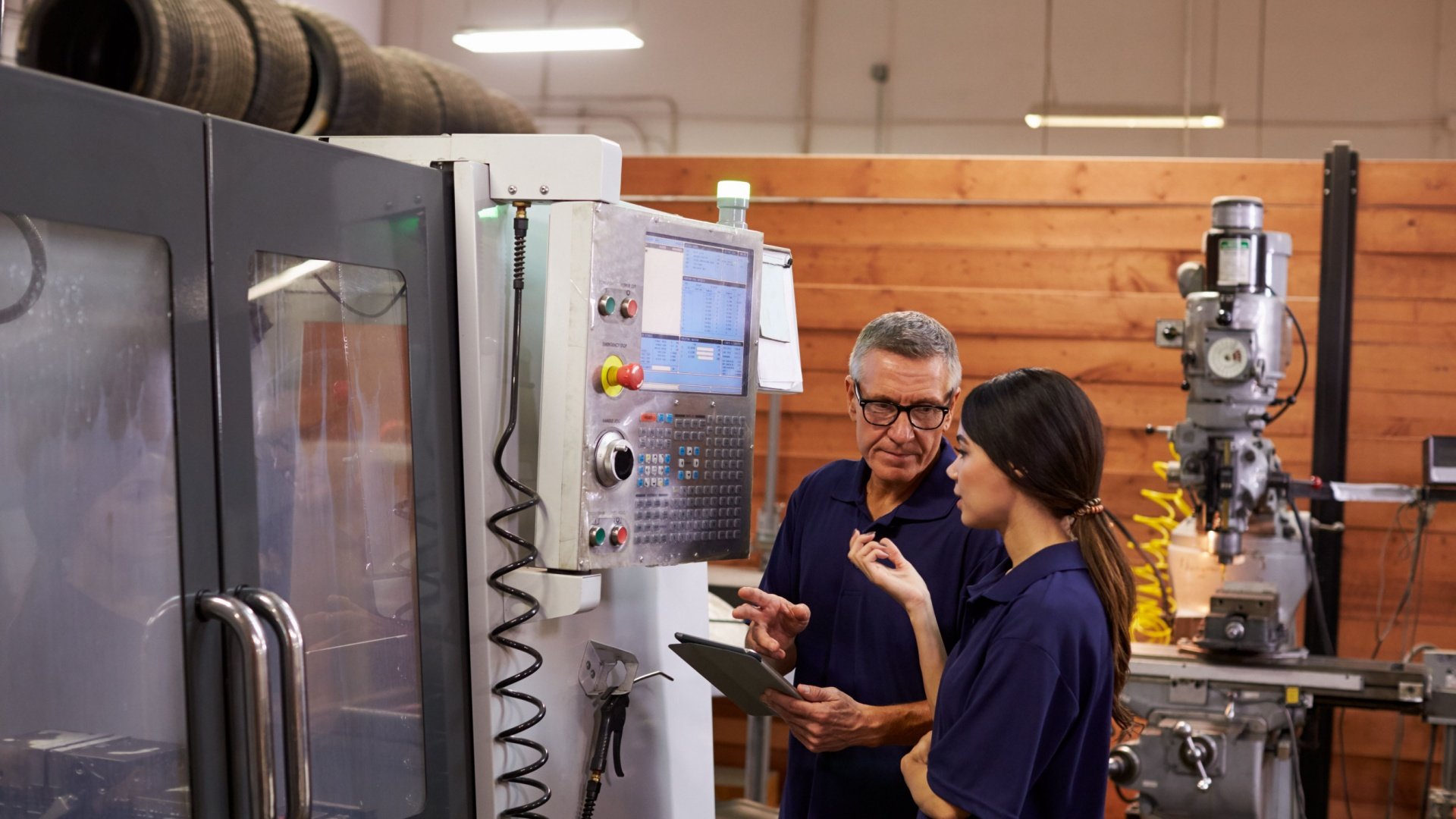Young apprentice learning to operate a CNC machine